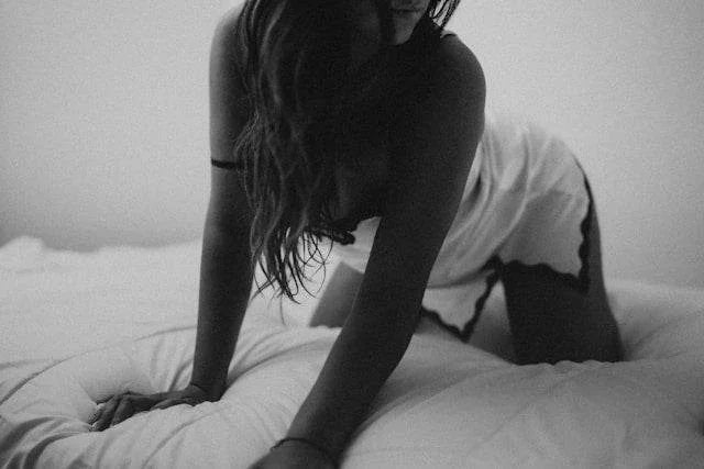 Kvinde i sanseligt natlet lingeri på sengekanten i dæmpet belysning – et intimt og æstetisk øjeblik, der afspejler Nevolas fokus på selvforkælelse og moderne sensuel wellness.