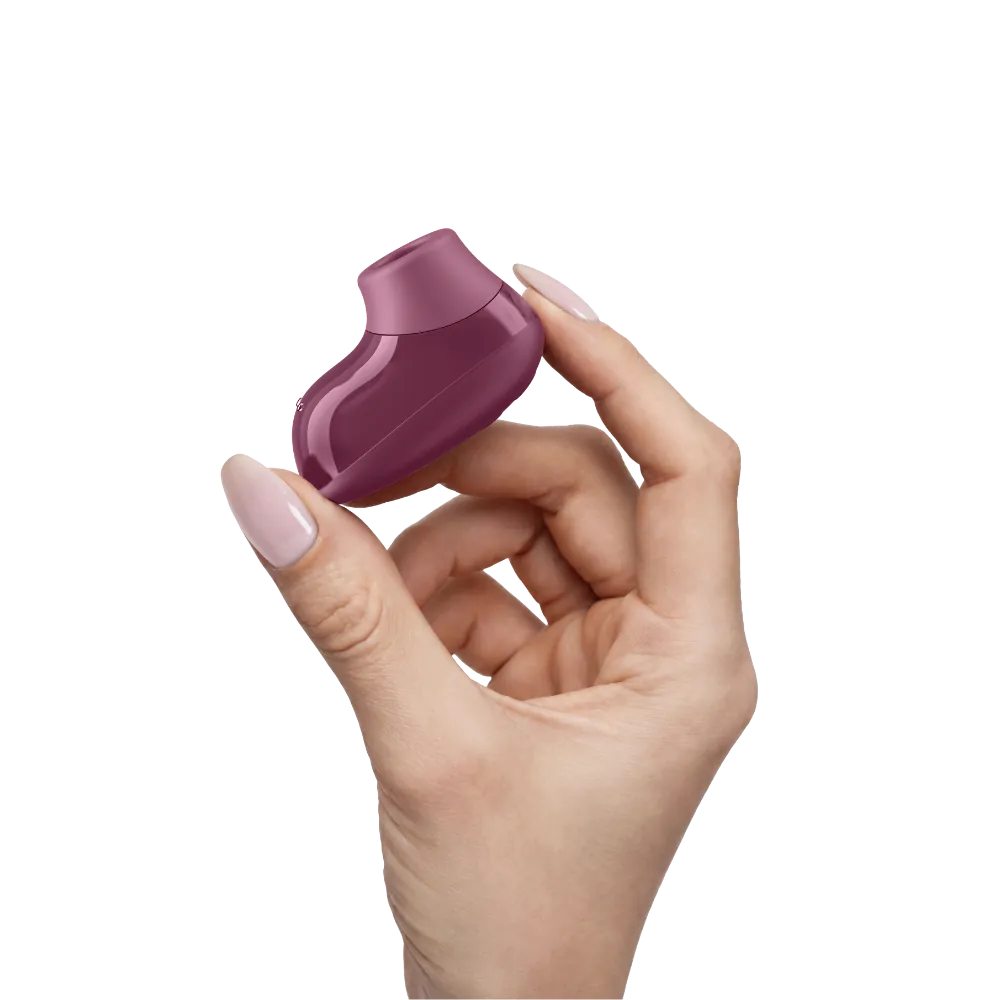 Womanizer Snap i Crushed Berry holdt mellem fingrene for at vise den kompakte størrelse