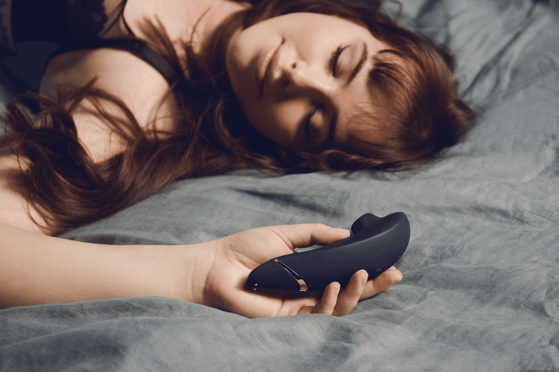 Kvinde ligger afslappet i sengen med en Ava Neo klitorisvibrator i hånden – et blidt øjeblik af selvforkælelse og nysgerrig opdagelse. Ideelt billede til Nevolas guide for nybegyndere.