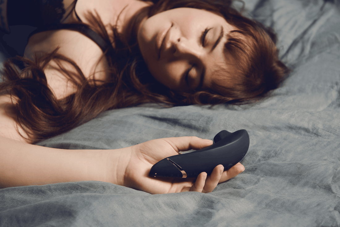 Kvinde ligger afslappet i sengen med en Ava Neo klitorisvibrator i hånden – et blidt øjeblik af selvforkælelse og nysgerrig opdagelse. Ideelt billede til Nevolas guide for nybegyndere.