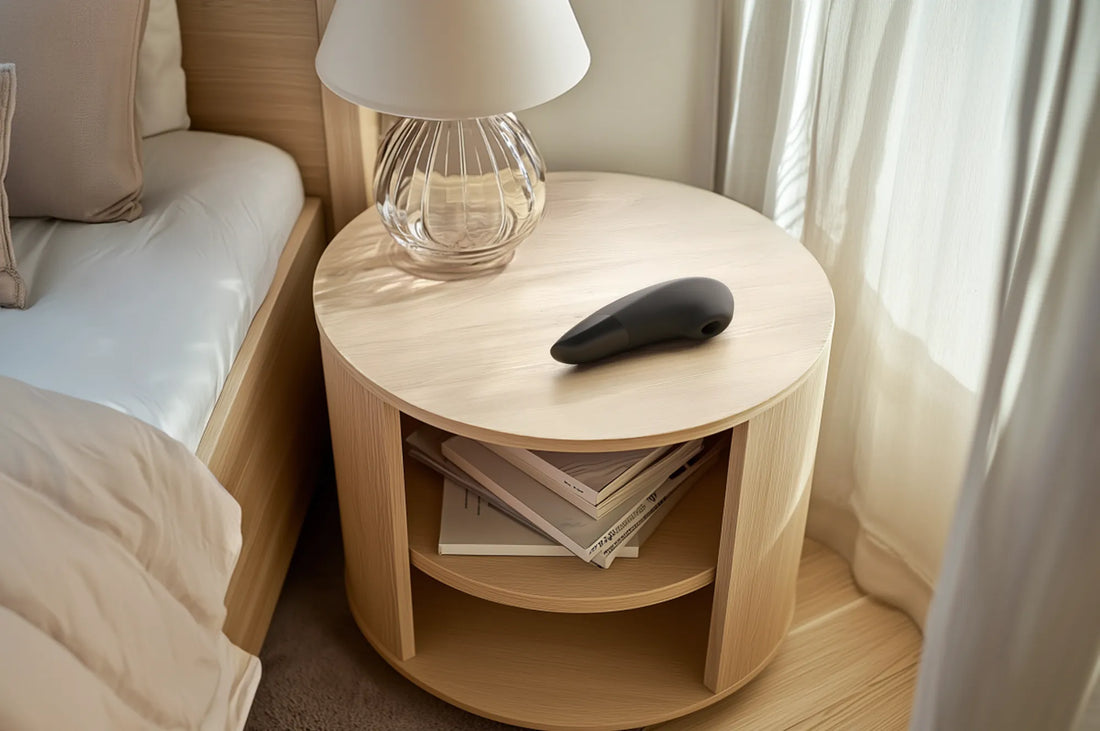 Womanizer i sort på sengebord.