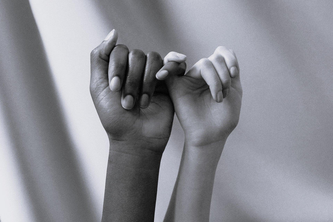 To hænder flettet sammen i pinky-swear gestus – symbol på tillid, forbindelse og sanselig forbundethed mellem to mennesker. Et poetisk billede på nærhed, respekt og gensidig støtte i intime relationer.