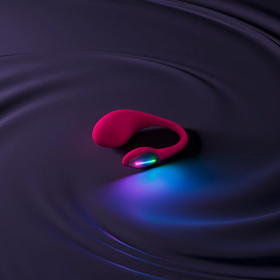 Lovense Lush 4 vist i mørk, sanselig baggrund med farverigt LED-lys. Elegant og luksuriøs præsentation af det pink vibratoræg, der understreger produktets moderne design og intime nydelse.