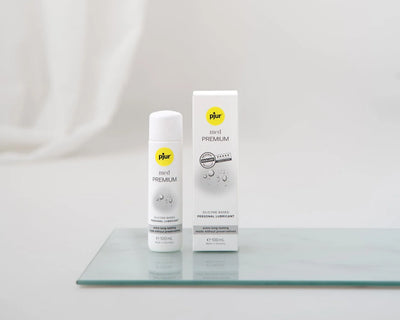 Pjur med Premium Glide 100ml – silikonebaseret glidecreme uden konserveringsmidler, velegnet til sensitiv hud og langvarig nydelse. Diskret og elegant flaske med matchende æske på glasplade.