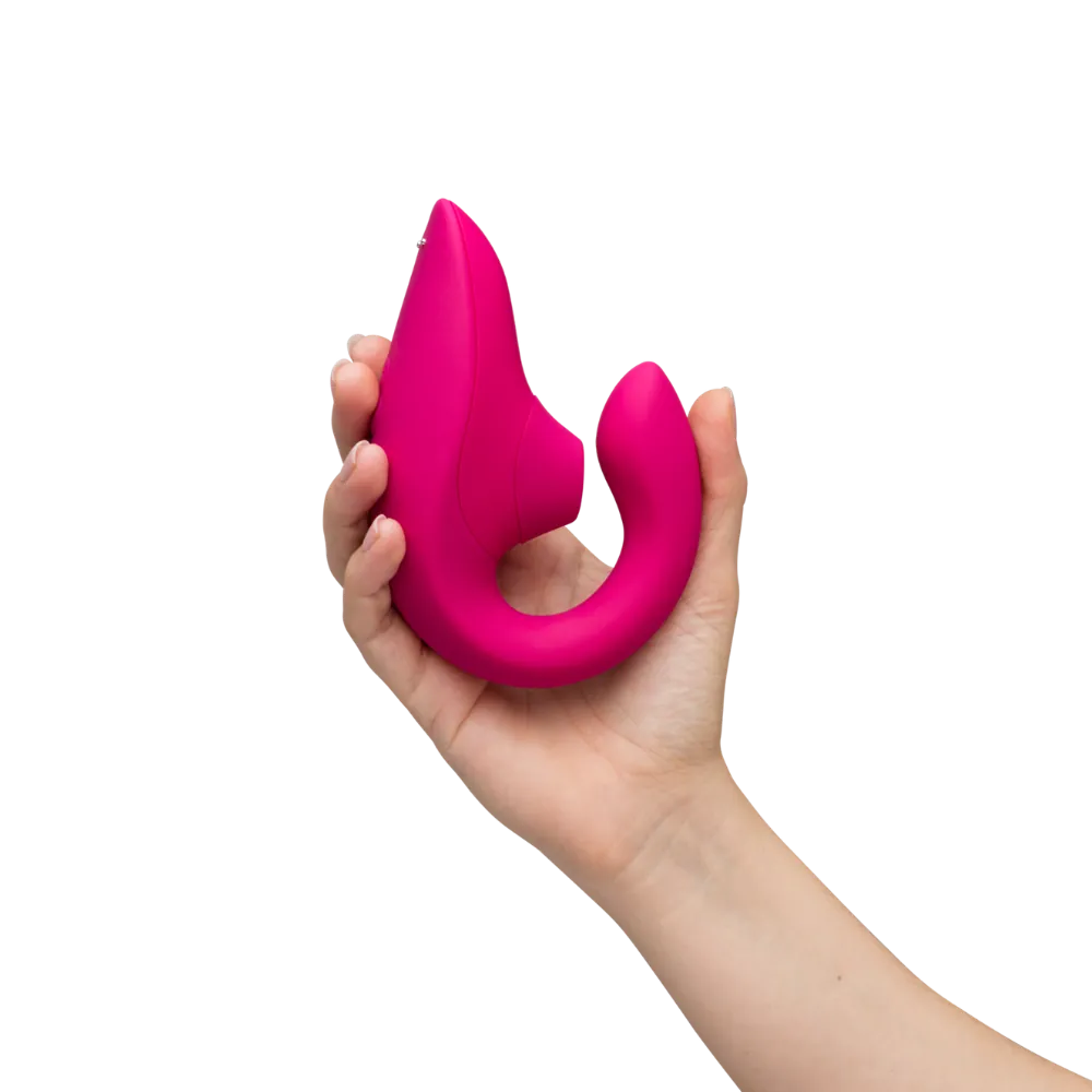 Womanizer Blend lufttryksvibrator i pink holdt i en kvindes hånd. Lifestylebillede der illustrerer sexlegetøjets størrelse og design.
