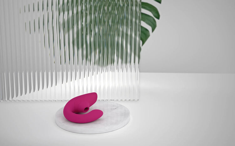 Womanizer Blend lufttryksvibrator i pink under vand omgivet af bobler. Produktbillede der illustrerer sexlegetøjets vandtætte konstruktion og egnethed til brug i bad eller spa.