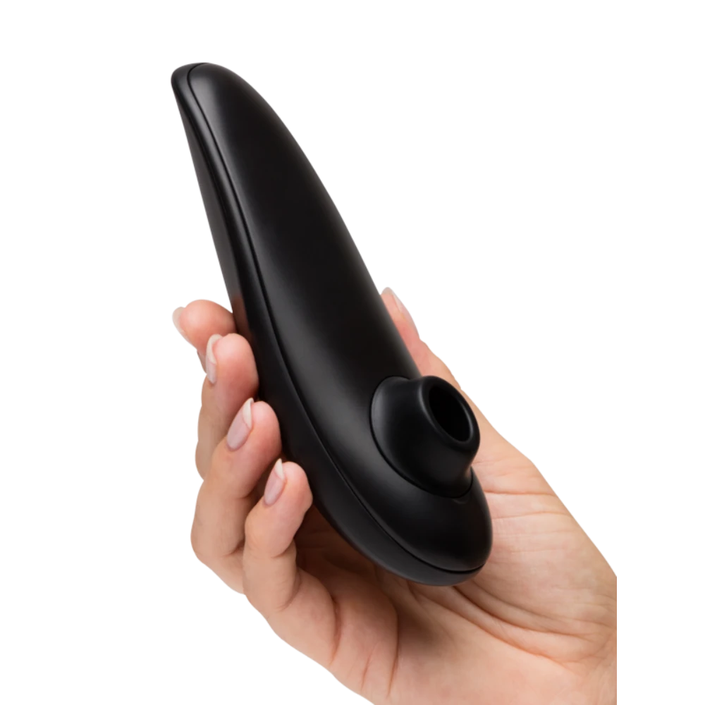 Hånd holder Womanizer Classic 2 lufttryksvibrator tæt, så stimulationshovedet fremhæves. Billedet viser sexlegetøjets ergonomiske design, diskrete størrelse og kvalitet i sensuel sort finish.