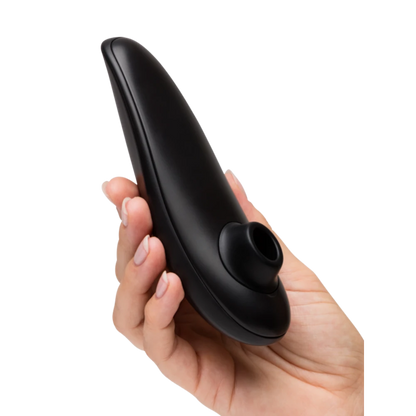 Hånd holder Womanizer Classic 2 lufttryksvibrator tæt, så stimulationshovedet fremhæves. Billedet viser sexlegetøjets ergonomiske design, diskrete størrelse og kvalitet i sensuel sort finish.