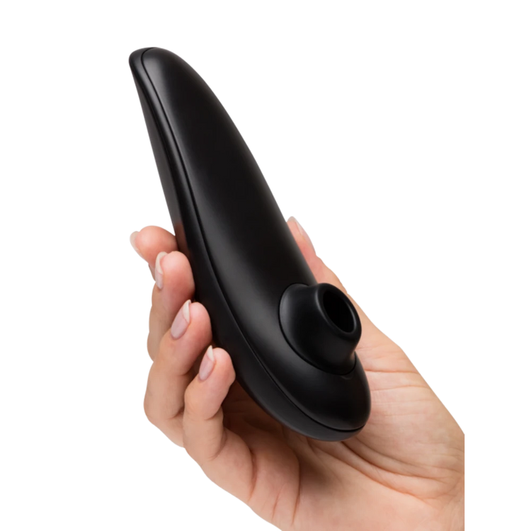 Hånd holder Womanizer Classic 2 lufttryksvibrator tæt, så stimulationshovedet fremhæves. Billedet viser sexlegetøjets ergonomiske design, diskrete størrelse og kvalitet i sensuel sort finish.