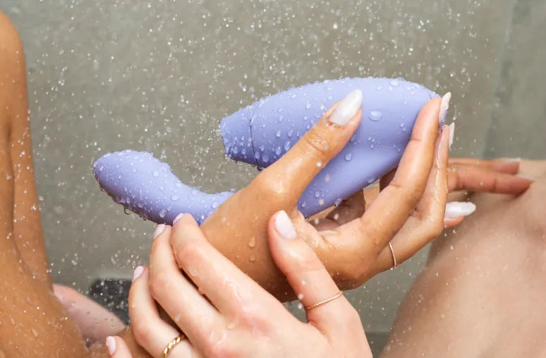 Kvinden holder Womanizer Duo 2 i badet, hvor det vandtætte sexlegetøj bruges i en afslappet og sanselig situation. Blød silikone, ergonomisk form og tryg brug i vand.