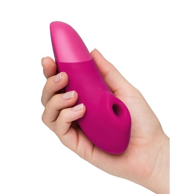 Womanizer Enhance vibrator i pink holdt i hånden, et eksklusivt sexlegetøj med Pleasure Air teknologi og vibrationsfunktion, skabt til sanselig nydelse, diskret stimulering og intim wellness i hverdagen.