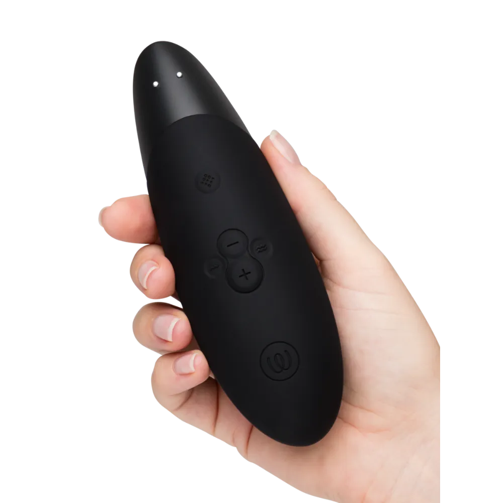 Womanizer Enhance vibrator i sort vist håndholdt med tydelige kontrolknapper, et stilfuldt sexlegetøj designet som intimprodukt til sanselig stimulering, tryg selvforkælelse og moderne wellness med brugervenlig styring.