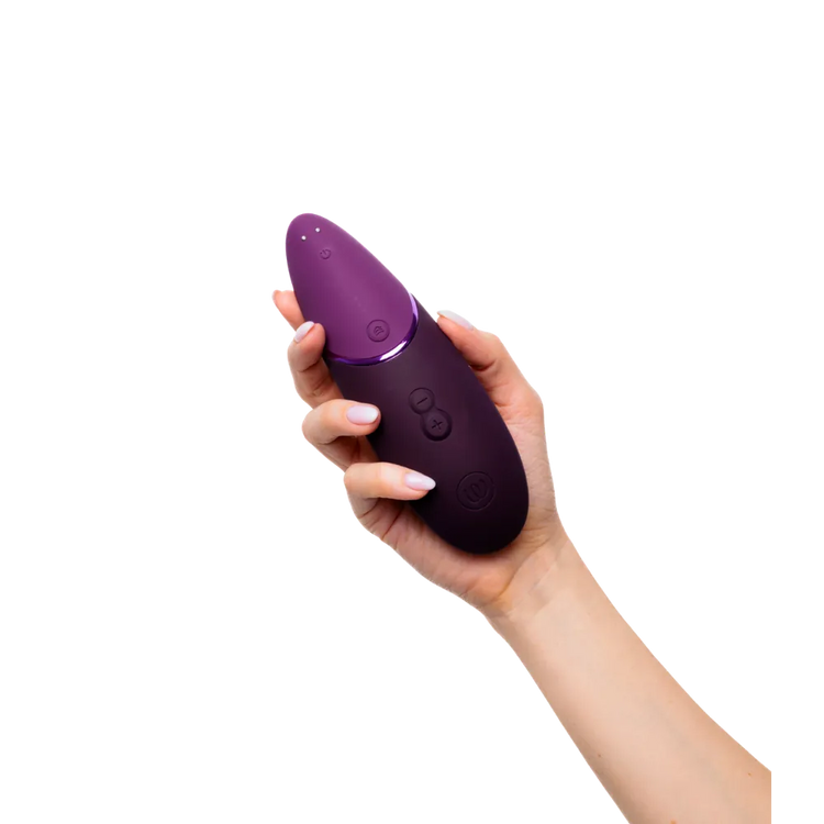 Womanizer Next i sort holdes i hånden set forfra. Fremhæver knappernes placering, designets renhed og brugervenlig kontrol.