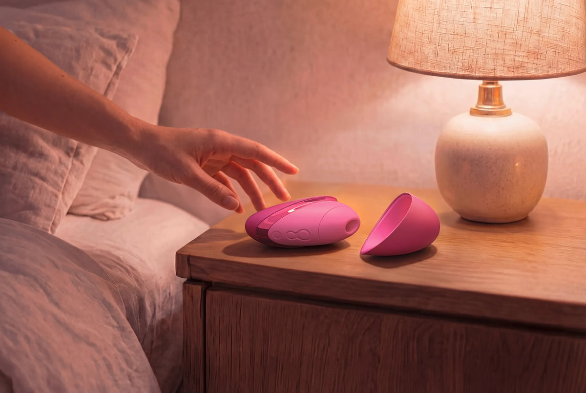 Womanizer Next Liberty i pink med det aftagelige cover placeret ved siden af produktet