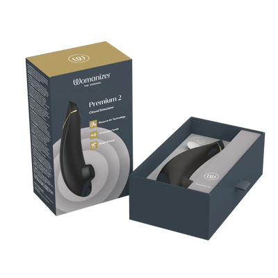 Womanizer Premium 2 clitoral stimulator i sort med gyldne detaljer, vist i original æske og åben emballage. Eksklusivt intimprodukt med Pleasure Air teknologi, 14 intensitetsniveauer og Smart Silence-funktion, til diskret og stilfuld nydelse hos Nevola.