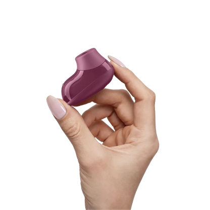 Womanizer Snap i Crushed Berry holdt mellem fingrene for at vise den kompakte størrelse